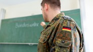 Ein Bundeswehrsoldat von der Seite vor einer Tafel, auf der Bundeswehr zu lesen ist. © Filmbildfabrik/Shotshop/picture alliance 