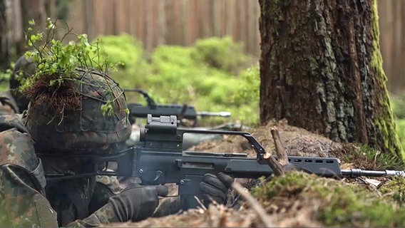 Soldaten der Bundeswehr liegen in einem Wald und schießen. © NDR 