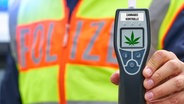 Ein Polizist hält ein Cannabis-Testgerät in der Hand. © picture alliance / CHROMORANGE Foto: Michael Bihlmayer