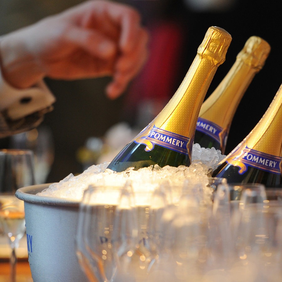 Eine Hand greift nach eisgekühlten Champagner-Flaschen © picture alliance / dpa Foto: Jens Kalaene