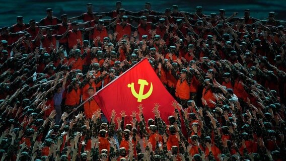 Bei Feierlichkeiten zum hundertjährigem Bestehen der Kommunistischen Partei Chinas ist im Zentrum einer Menschenformation eine chinesische Flagge zu sehen. © dpa Foto: Ng Han Guan