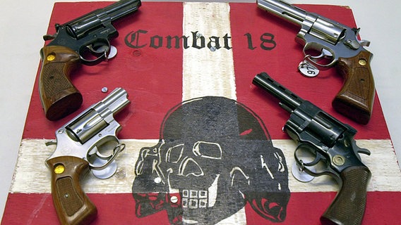 Sichergestellte Waffen und ein Schild der kriminellen Neonazi-Gruppe "Combat 18" liegen im schleswig-holsteinischen Landeskriminalamt in Kiel. © dpa - Fotoreport Foto: Horst Pfeiffer