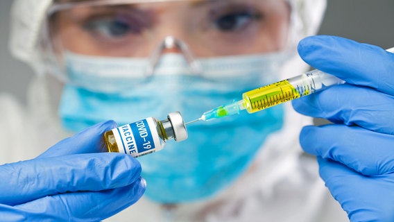 Eine Wissenschaftlerin hält eine Ampulle mit Impfstoff gegen das Coronavirus. © imago images/Cavan Images 