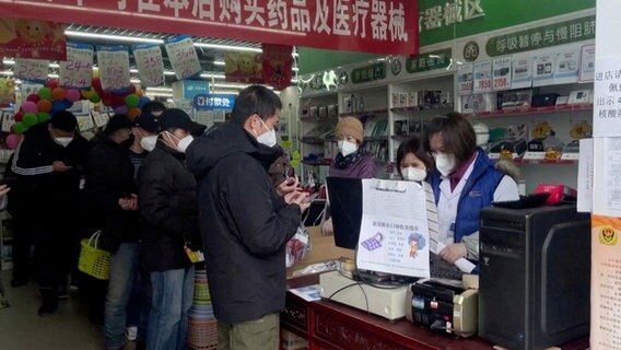 Mehrere Menschen mit Schutzmasken stehen in einer Apotheke in China Schlange. © Reuters 