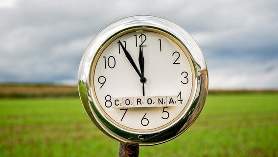 Die Zeiger einer Uhr mit der Aufschrift "Corona" stehen auf fünf vor zwölf. © picture alliance / Fotostand / K. Schmitt 
