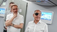 Bundeskanzler Olaf Scholz (r, SPD) und Christian Lindner (FDP), Bundesminister der Finanzen, sprechen auf dem Flug nach Neu Dehli zum G20-Gipfel mit den mitreisenden Journalisten. © dpa Foto: Kay Nietfeld