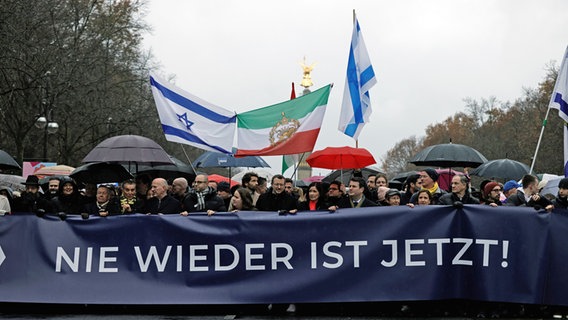 Teilnehmer einer Demonstration protestieren unter dem Motto "Deutschland steht auf - Nie wieder ist jetzt!" gegen Antisemitismus. In der ersten Reihe halten unter anderem Rabbi Jehuda Teichtal, Bundestagspräsidentin Bärbel Bas (SPD), Musiker Roland Kaiser, Publizist Michel Friedman, Berlins Oberbürgermeister Kai Wegner (CDU), Grünen-Vorsitzende Ricarda Lang und Bundesarbeitsminister Hubertus Heil (SPD) ein Plakat mit der Aufschrift "Nie wieder ist jetzt". © Carsten Koall/dpa 