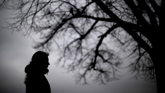 Eine Frau steht neben einem kahlen Baum © dpa Foto: Julian Stratenschulte