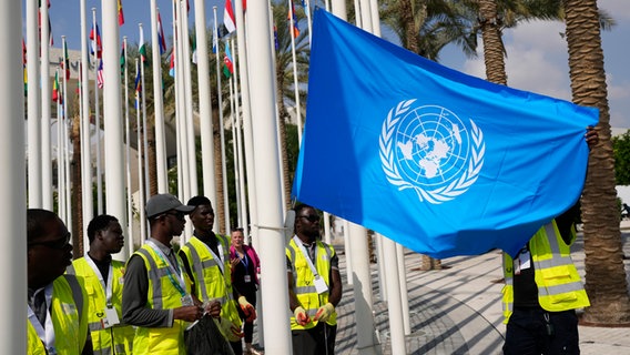 Die Flagge der Vereinten Nationen wird vor dem UN-Klimagipfel in Dubai aufgehangen. © Rafiq Maqbool/AP/dpa 