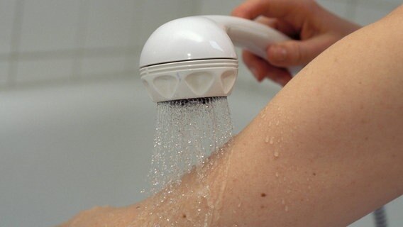 Wasser läuft aus einem Duschkopf über einen Arm © MAGO / Niehoff Foto: Niehoff