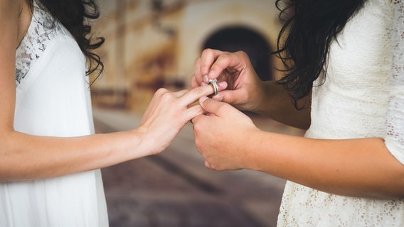 Eine Frau streift einer anderen Frau einen Brilliantring über den Ringfinger. © fotolia Foto: Fotos 593