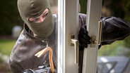 Maskierter Einbrecher bricht ein Fenster auf. © Fotolia.com Foto: bilderbox