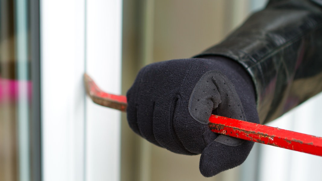 Einbrecher hebelt mit einem Brecheisen ein Fenster auf.