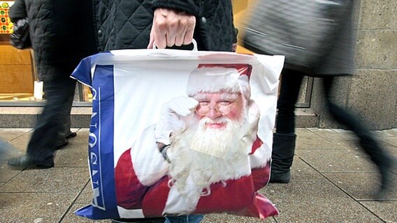 Ein Mann trägt eine Tüte, auf der ein Weihnachtsmann abgebildet ist © dpa Foto: Ulrich Perrey
