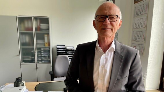 Jürgen Allemeyer, Geschäftsführer des Studierendenwerks in Hamburg, steht in seinem Büro auf einem Stehtisch. Im Hintergrund ist sein Schreibtisch zu sehen. © NDR Info Foto: Lisa Hentschel
