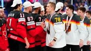 Deutschlands Nico Sturm schüttelt dem Kanadier Lawson Crouse nach dem Spiel die Hand. © Pavel Golovkin/AP 