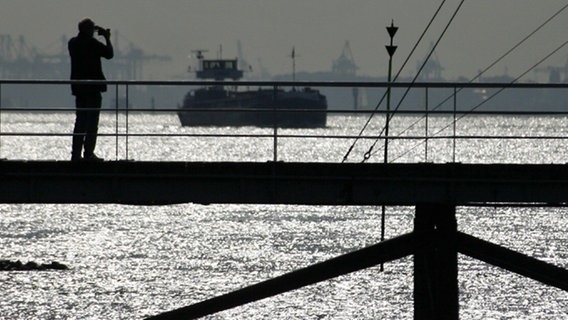 Ein Mann steht in Wedel auf dem Steg der Schiffsbegrüßungsanlage an der Elbe © dpa Foto: Mauruzio Gambarini