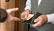 Senior übergibt einem Täter Geld an der Haustür © imago images 
