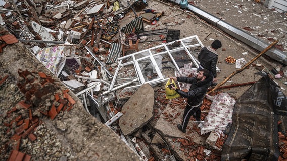 Menschen und Rettungskräfte suchen in Gaziantep nach Menschen in den Trümmern eines zerstörten Gebäudes. © AP/dpa Foto: Mustafa Karali
