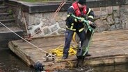 Ein Taucher der Feuerwehr bringt einen E-Scooter ans Ufer der Alster. Während der Stadtputzaktion "Hamburg räumt auf!“ haben Taucher der Polizei, Feuerwehr und der DLRG nach Müll und Schrott in der Alster gesucht. © picture alliance Foto: Marcus Brandt