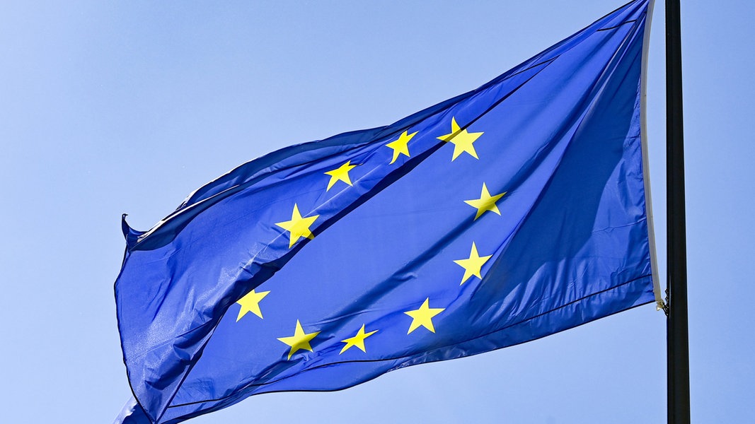 Die EU-Flagge weht vor blauem Himmel im Wind