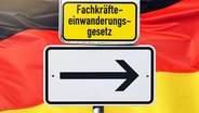Ein Schild mit einem Pfeil und der Aufschrift Fachkräfteeinwanderungsgesetz vor einer deutschen Flagge © picture alliance / CHROMORANGE Foto: Christian Ohde