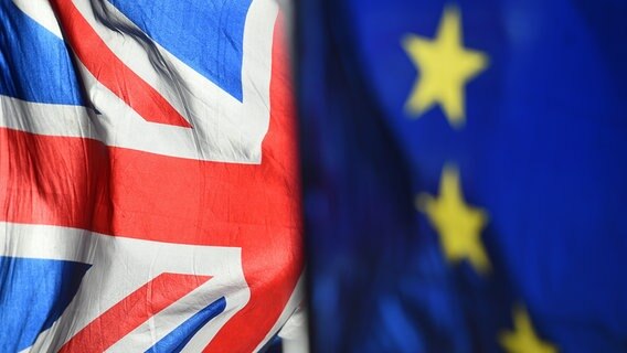 Die Flaggen Großbritanniens und der EU wehen nebeneinander und sind jeweils etwa zur Hälfte zu sehen. © dpa picture alliance / empicss Foto: Kirsty O'Connor