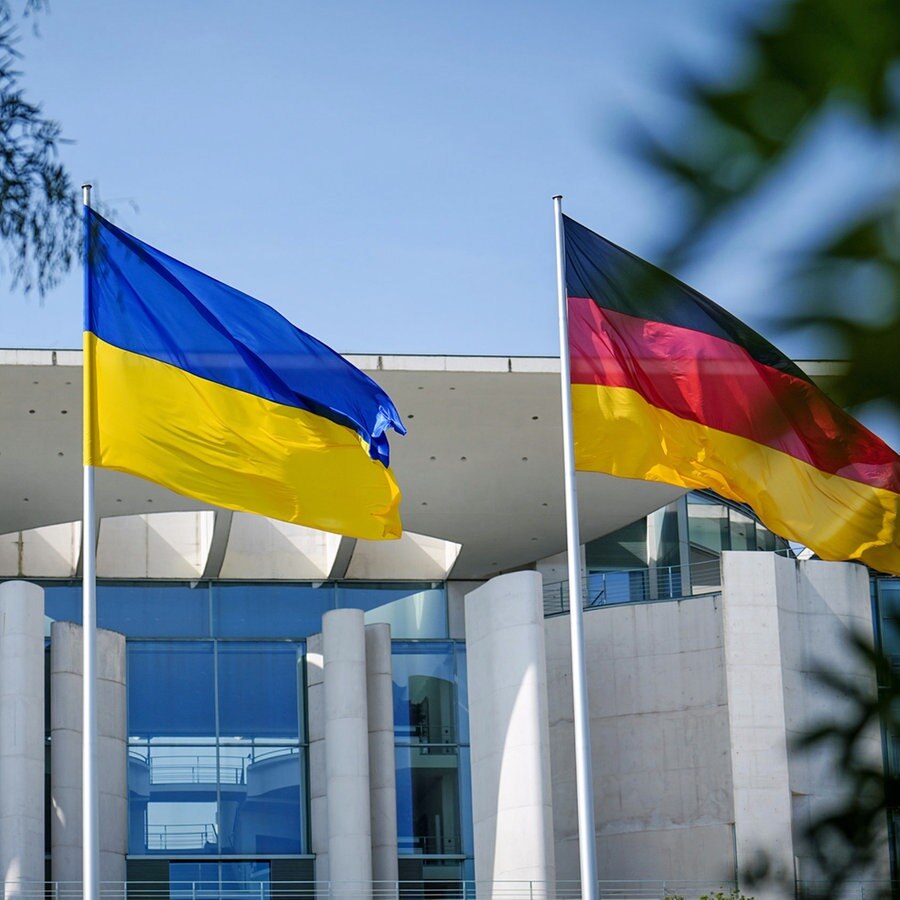 Die Fahne der Ukraine weht zwischen der europäischen (l.) und deutschen Fahne (r.) vor dem Bundeskanzleramt in Berlin. © Kay Nietfeld/dpa 