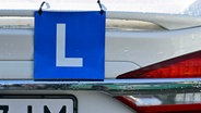 Ein blaues Schild mit weißem L - das Symbol für Lernfahrausweis - hängt am Heck eines Autos. © picture alliance / imageBROKER | Pius Koller 