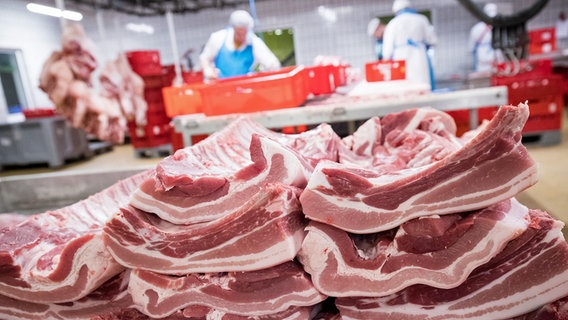 Arbeiter in einem Fleischzerlegebetrieb. Im Vordergrund sind Rippen und Bauchfleisch vom Schwein zu sehen. © dpa picture alliance Foto: Christian Charisius