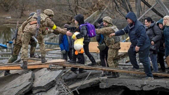 Ukrainische Soldaten helfen einer fliehenden Familie bei der Überquerung des Flusses Irpin in den Außenbezirken von Kiew © AP/dpa Foto: Emilio Morenatti