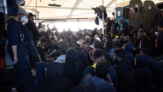 Die von der Hilfsorganisation SOS Humanity herausgegebene Aufnahme zeigt aus dem Mittelmeer gerettete Flüchtlinge, die an Deck des deutschen Seenotrettungsschiffes "Humanity 1" sitzen. © Max Cavallari/SOS Humanity/dpa 