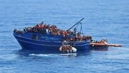 Mit Schlauchbooten retten Mitarbeiter der Organisation Ärzte ohne Grenzen Migranten und Flüchtlinge im Mittelmeer von einem Boot mit mehr als 600 Menschen in Seenot. © picture alliance/dpa/MSF | - 