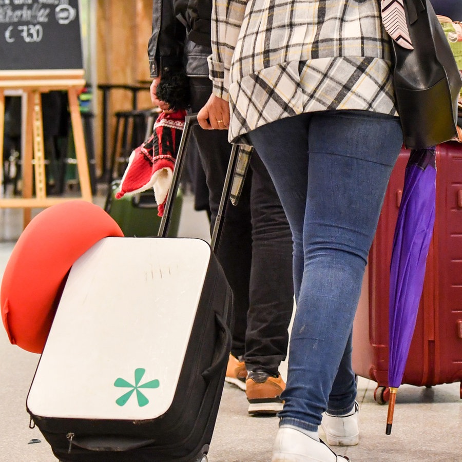 Passagiere gehen mit ihren Koffern durch eine Ankunftshalle eines Flughafengebäudes © picture alliance/dpa Foto: Jens Kalaene