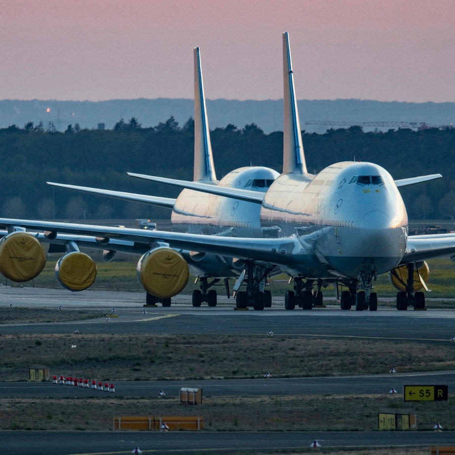 Mit abgedeckten Turbinen stehen vorübergehend stillgelegte Passagiermaschinen der Lufthansa auf dem Rollfeld des Frankfurter Flughafens © picture alliance/dpa Foto: Boris Roessler