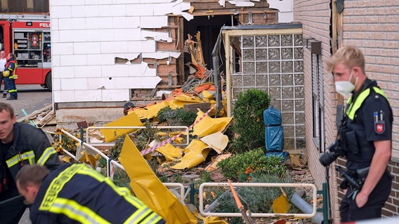 Die Trümmer eines Sportflugzeugs liegen an den Mauern eines teilweise beschädigten Hauses. Rettungskräfte stehen davor. © picture alliance Foto: Christian Gossmann