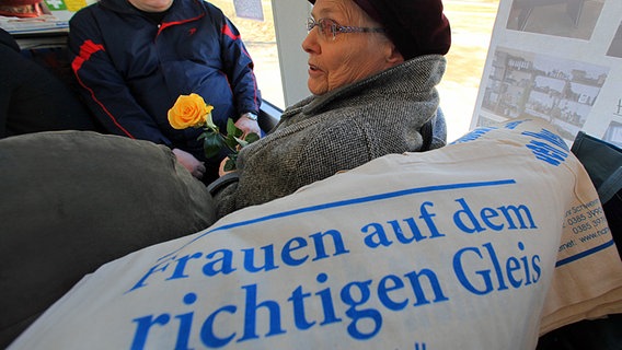 Eine Frau mit einer gelben Rose sitzt in einer Straßenbahn in Schwerin. © dpa picture alliance Foto: Jens Büttner