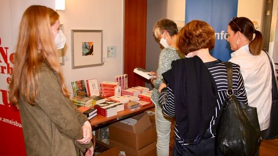 Menschen mit Maske schauen sich Bücher an. © NDR Foto: Jenny von Gagern