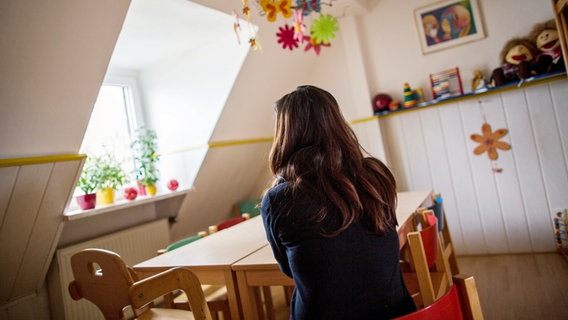 Eine Frau sitzt in einem Frauenhaus in einem Zimmer. © picture alliance / dpa Foto: Maja Hitij