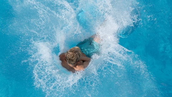 Ein Junge springt im Freibad ins Wasser © Sebastian Kahnert/dpa 