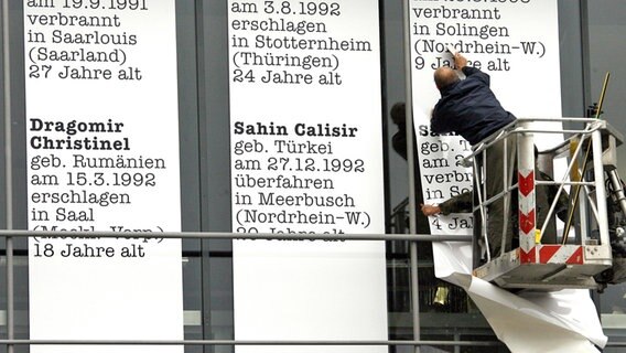 Mann klebt Pkalate mit Namen von Opfern rechter Gewalt in Deutschland an die Fassade der Akademie der Künste in Berlin. © picture-alliance / dpa Foto: Wolfgang Kumm