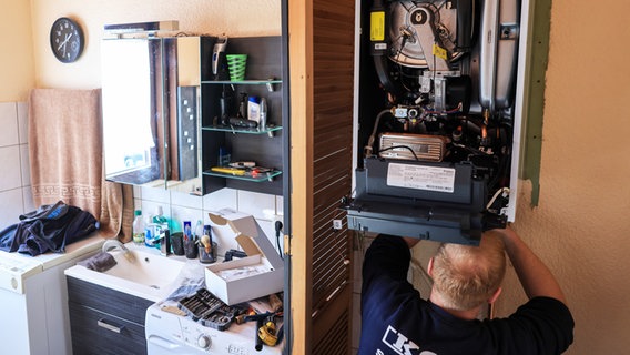 Ein Mitarbeiter einer Sanitär- und Heizungsbaufirma installiert eine moderne Gasbrennwerttherme in einem Einfamilienhaus. © picture alliance Foto: Jan Woitas