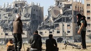 Bewohner eines Wohnkomplexes in Chan Junis im südlichen Gazastreifen sitzen nach einem israelischen Angriff vor den zerstörten Häusern. © dpa-Bildfunk/SOPA Images via ZUMA Press Wire Foto: Ahmed Zakot