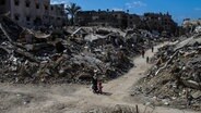 Dschabalia: Menschen gehen an den Ruinen von Gebäuden vorbei. © dpa Foto: Mahmoud Issa