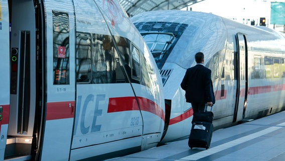 Ein Reisender zieht einen Rollkoffer neben einem ICE auf dem Bahnsteig des Berliner Hauptbahnhofs.  