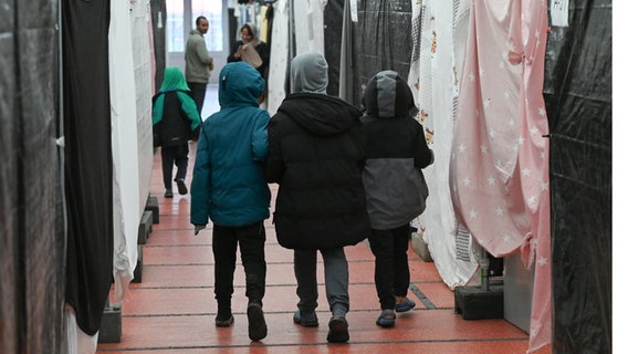 Flüchtlingskinder gehen durch ein Zelt einer Flüchtlingsunterkunft © Arne Dedert/dpa 