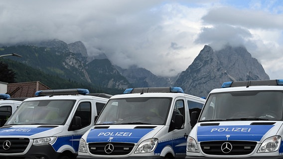 Polizei-Mannschaftswagen parken in Garmisch-Partenkirchen vor einer Bergkulisse. © dpa bildfunk Foto: Angelika Warmuth
