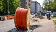 Kabeltrommel mit Glasfaserkabel auf einem Gehweg in einem Wohnviertel. © picture alliance Foto: Rupert Oberhäuser