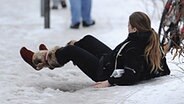 Ein Frau liegt nach einem Sturz auf dem vereisten Gehweg © dpa 