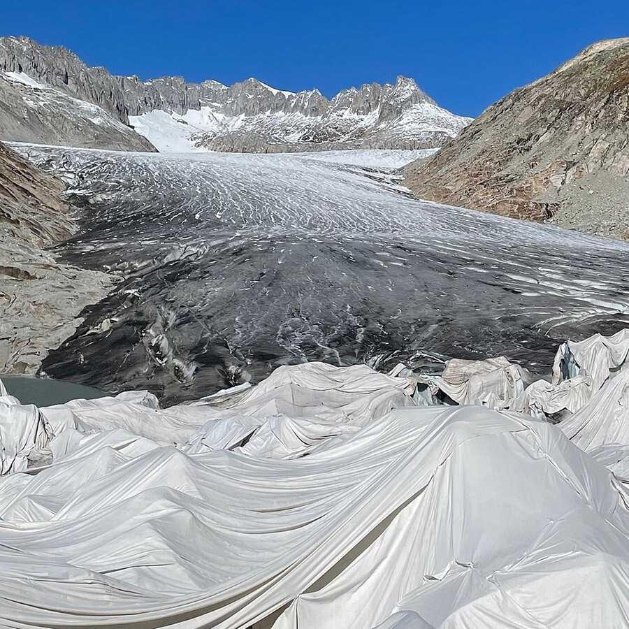 Helle Textilplanen decken Teile des Gletschers ab, um das Schmelzen zu verlangsamen. © ARD Foto: Kathrin Hondl